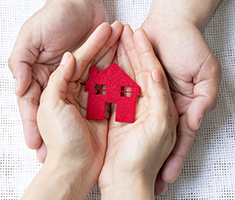 Two People's Hands Holding a Felt House