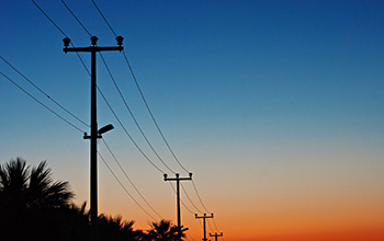 Row of utility poles with sunset in background