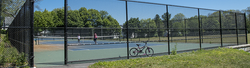 Kids Playing Tennis on the Fenced-In Court at Greenwood Park