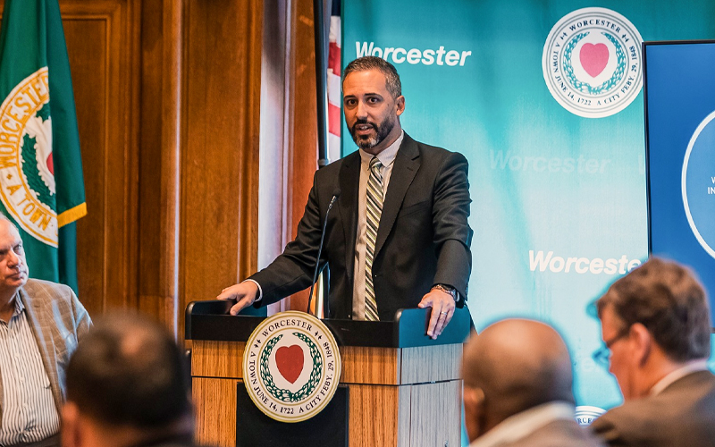City Manager Eric Batista Standing at Podium in Front of Crowd of Onlookers