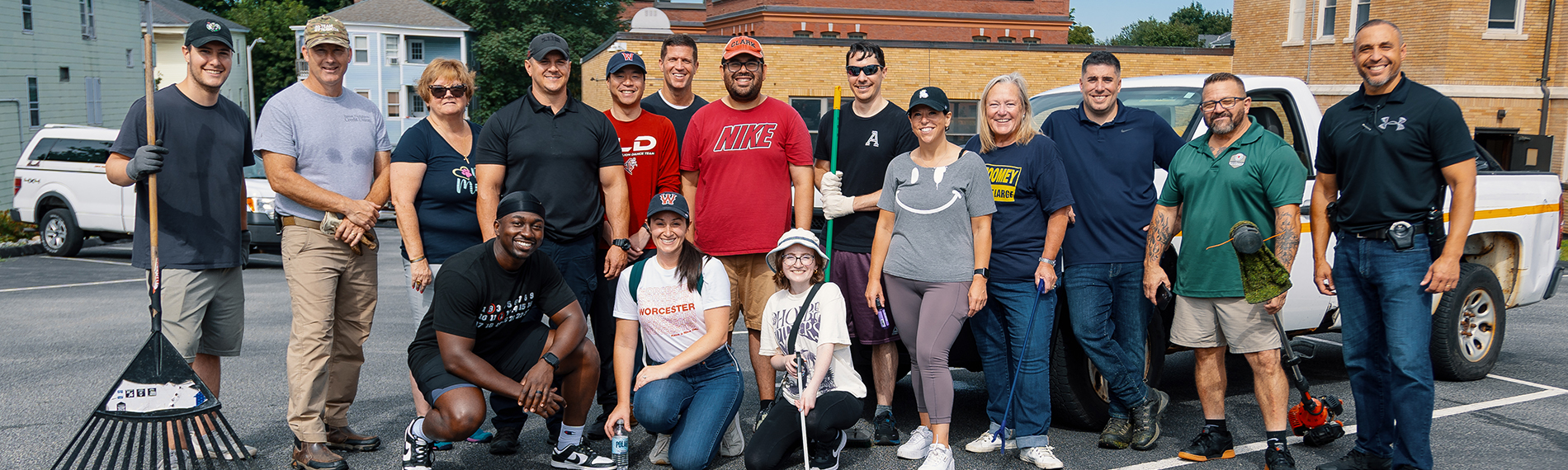 Group Photo of Members of Quality of Life Team Standing in Parking Lot Holding Rakes and Yard Tools