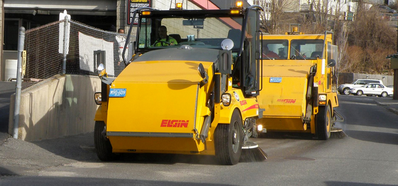 Two Street Sweepers Picking Up Street Sand