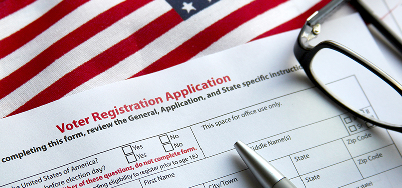 Pen Resting on Voter Registration Application with American Flag in Background