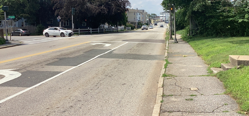 Two Travel Lanes and Sidewalk of Massasoit Road with Pavement in Disrepair
