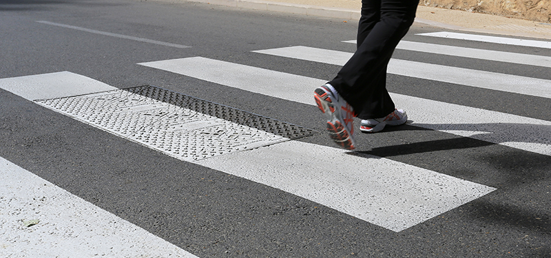 Legs and Feet of Person Crossing the Street in a Crosswalk