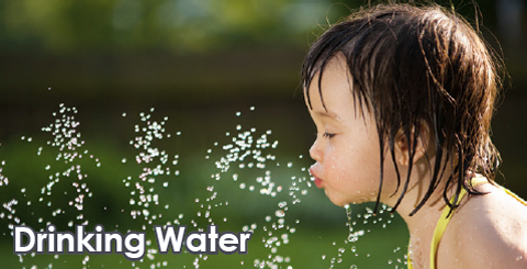 Girl in Bathing Suit Drinking Water from Sprinkler