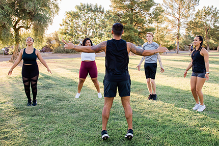 Group of People Doing Jumping Jacks in Field