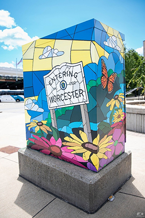 Art Wrapped Electrical Box on Sidewalk with Stained Glass Like Imagery of Entering Worcester Sign