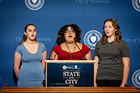 Three Students at Podium Singing National Anthem to the Audience
