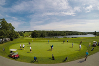 Many Golfers Practicing Putting on a Practice Green Before a League Round with Pond in the Background - Click to Enlarge