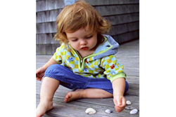 Toddler Sitting on Wooden Deck Playing With Shells and Rocks 
