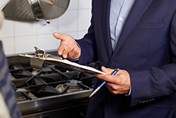 Inspector Holding a Clipboard in a Restaurant Kitchen Near a Stove