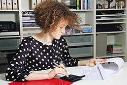 Female Intern Sitting at a Desk with Papers and a Calculator