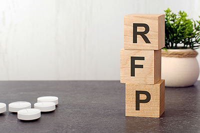 Wooden Block Letters R, F, and P Stacked on a Table with Five White Pills on Left of Table
