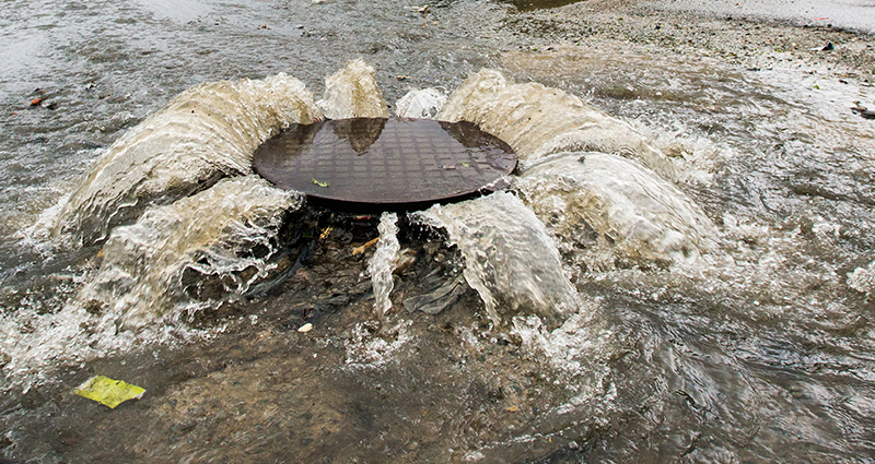 Sewer Cover with Water/Sewage Pouring Out Onto Street