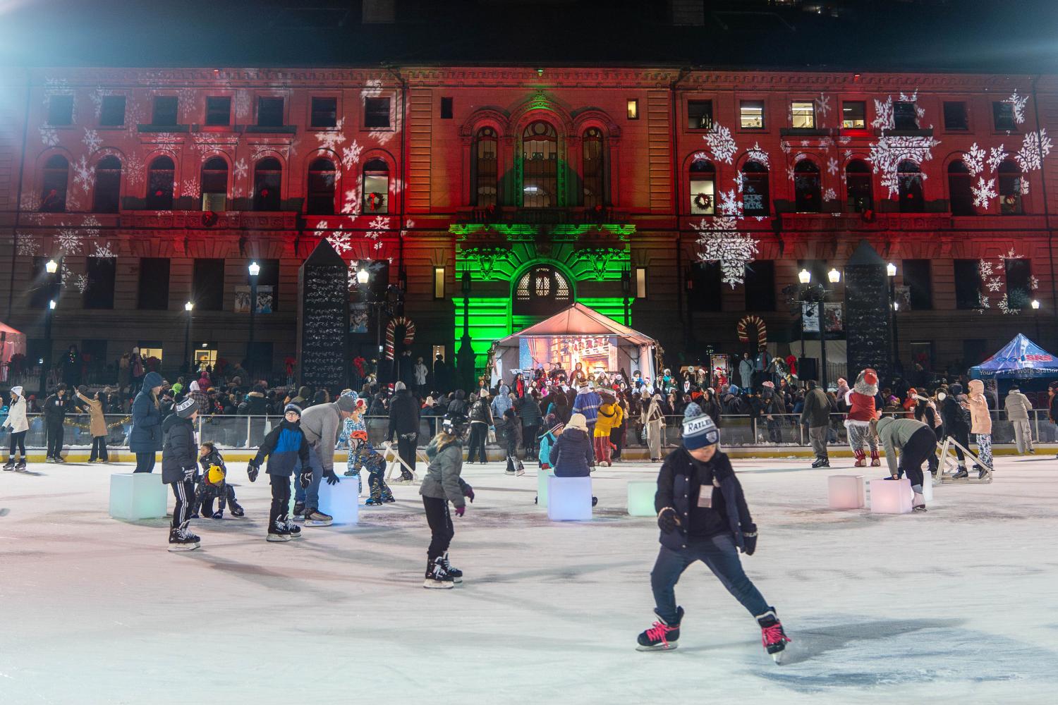 Children skate behind city hall which is lit up green and red at the annual Festival of Lights