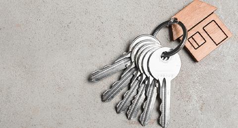 Set of Keys with Wooden House Keychain Sitting on Gray Table