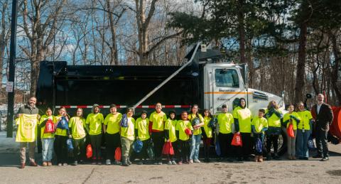 Group of School Children Wearing Yellow Shirts with City Manager Standing in Front of Large DPW Snowplow
