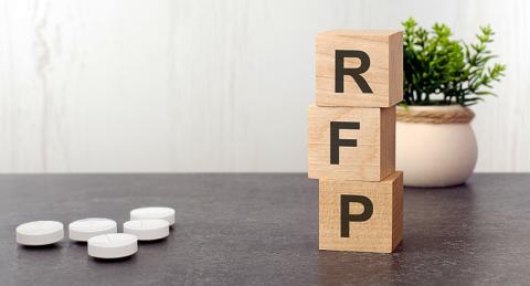 Wooden Block Letters R, F, and P Stacked on a Table with Five White Pills on Left of Table
